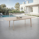 Outdoor dining table with bowls on a patio near a pool and modern house.