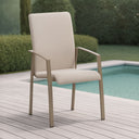 Beige outdoor chair on a wooden deck by a pool with greenery in the background