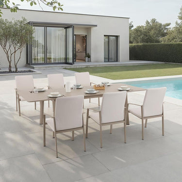Outdoor dining set with table and chairs near a modern house and pool.
