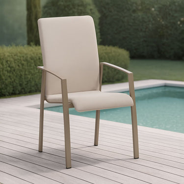 Beige outdoor chair on a wooden deck by a pool with greenery in the background